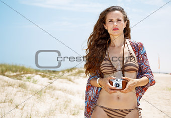 Bohemian woman with retro photo camera on white beach