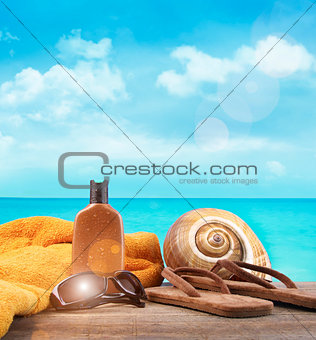 Suntan lotion with towel and sandals at the beach
