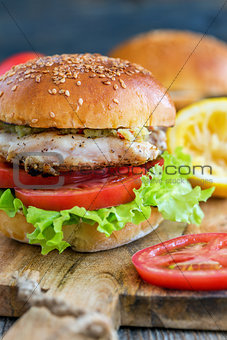 Tasty burger with chicken, tomato and spicy sauce.