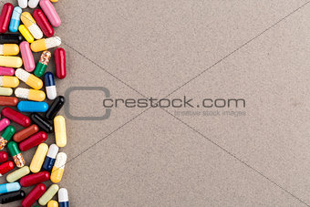 Various colorful capsules and pills on brown craft paper