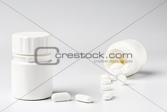 White plastic pill bottles and heap of various pills