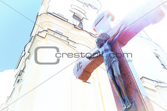 Jesus on wooden cross in a background of church with glimpse sunshine