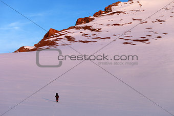 Hiker in sunrise snowy mountains