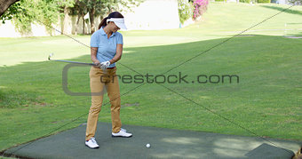 Young female golfer preparing to tee off