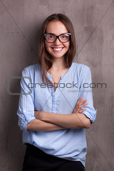 portrait of beautiful happy young woman with glasses near grey background wall