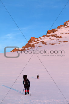 Two hikers in sunrise snowy plateau