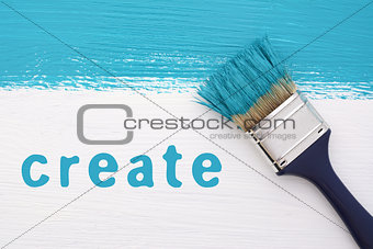 Stripe of turquoise paint, paintbrush and the word CREATE