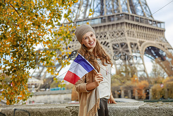elegant woman on embankment near Eiffel tower showing flag
