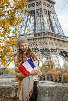 smiling elegant woman on embankment in Paris, France with flag