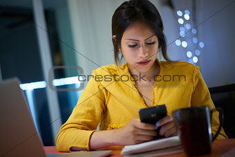 College Student Studying At Night Types Message On Phone