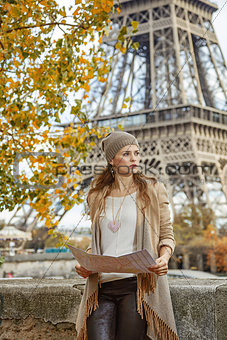 elegant woman holding map and looking into the distance in Paris