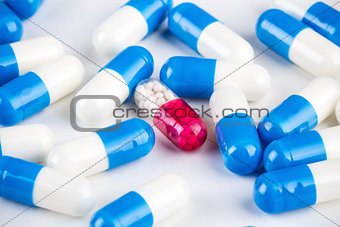 Blue capsules around pink transparent capsule on white