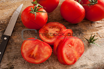 Sliced succulent red tomatoes beside serrated knife