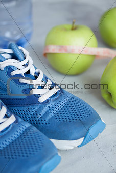 Sport shoes, meter, apples, bottle of water on gray concrete bac