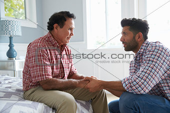Adult Son Comforting Father Suffering With Dementia