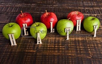 Green and red organic healthy apples on wooden board