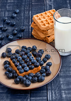 Blueberries and waffles on plate with milk glass