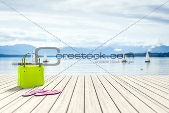 green bag on a wooden jetty with sailing boats in the background