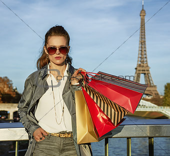 trendy woman in trench coat with shopping bags in Paris, France