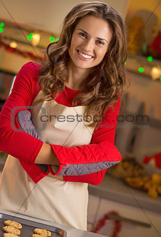 Portrait of happy young housewife with pan of fresh cookies in c