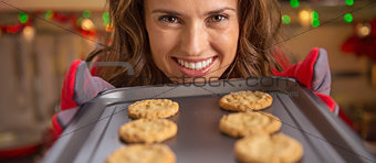 Happy young housewife showing pan with christmas cookies