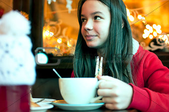 Girl with a cup of tea in a cafe eating Christmas cookies and lo