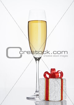 Glass of sparkling champagne with red gift box