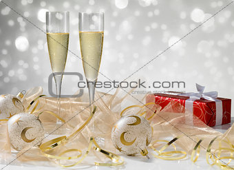 Two champagne glasses, golden decoration. Red gift with white ri