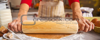 Closeup on housewife rolling out dough with rolling pin