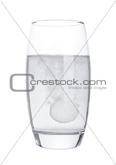 Pill dissolving in glass of water on white