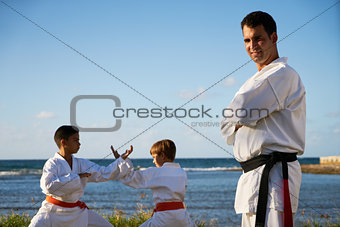 Portrait Of Confident Karate Trainer Watching Children Fight