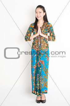 Southeast Asian woman in batik dress greeting