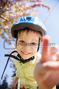 Young boy in helmet looking at camera and going to touch it