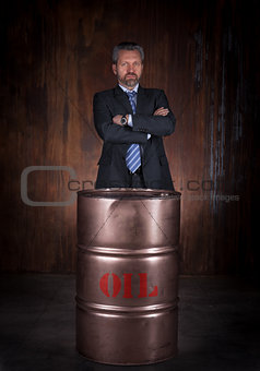 Mature businessman and barrel of crude oil on dark background