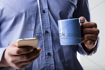 hands with smartphone and a mug