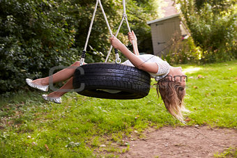 Young Girl Playing On Tire Swing In Garden