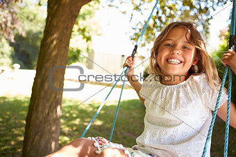 Portrait Of Young Girl Playing On Tree Swing