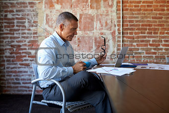 Mature Businessman Working On Laptop In Boardroom