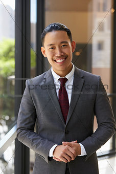 Young Asian businessman smiling to camera, vertical