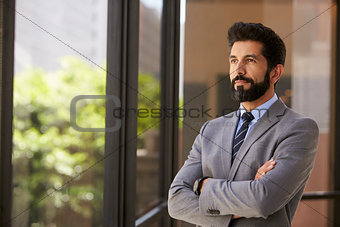 Middle aged Hispanic businessman looks out of office window