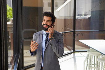 Smiling middle aged Hispanic businessman on phone in office