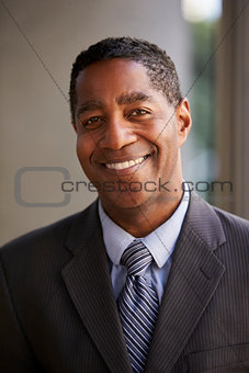 Middle aged black businessman smiling to camera, vertical