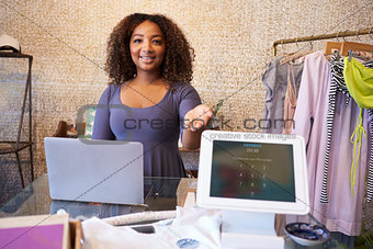 Assistant at clothing store shows computer used for payment
