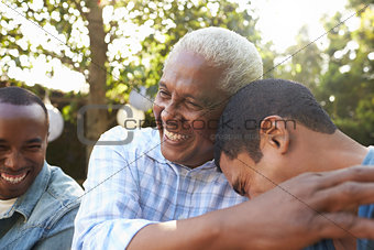 Senior man greeting his two adult sons in garden, close up