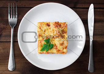Close-up of a traditional lasagna topped with parskey leafs served on a white plate