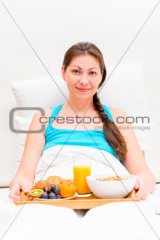 a woman with a tray of breakfast in bed in the morning