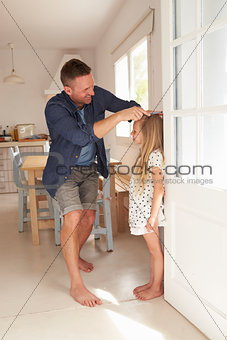 Father Measuring Daughter's Height Against Wall