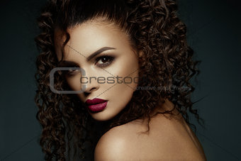 Beautiful face of a fashion model with black eyes.Curly hair. Red lips.