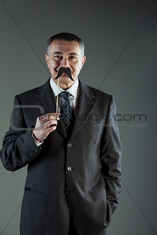 Smiling businessman holding a mustache