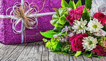 bouquet of fresh flowers and gift box on wooden table